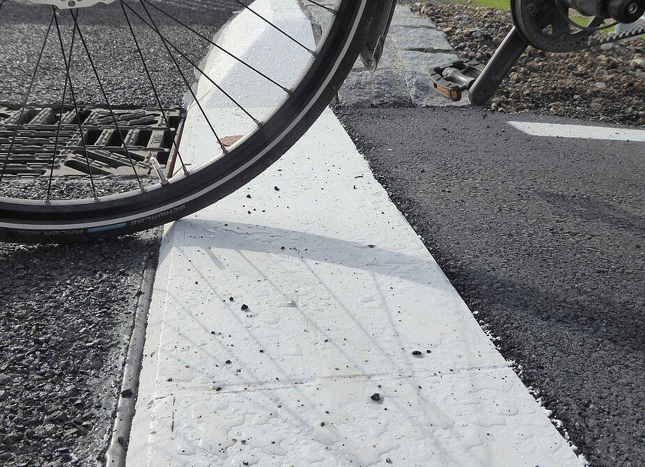 Während an der neuen Radweg-Furt am Schneiderkreisel ebene Übergänge gebaut wurden, gibt es beim neuen Kreisverkehr ca. 2 cm hohe Absätze. Das ist vor allem auf der Seite, wo gar kein Wasser geführt werden muss, völlig unnötig!