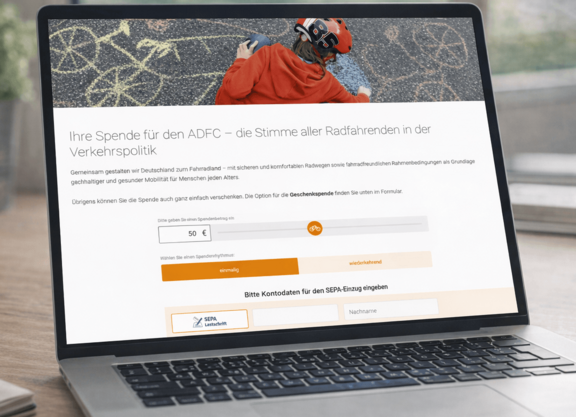 Ein Laptop steht auf einem Tisch. Auf dem Bildschirm ist die Spendenseite des ADFC zu sehen.